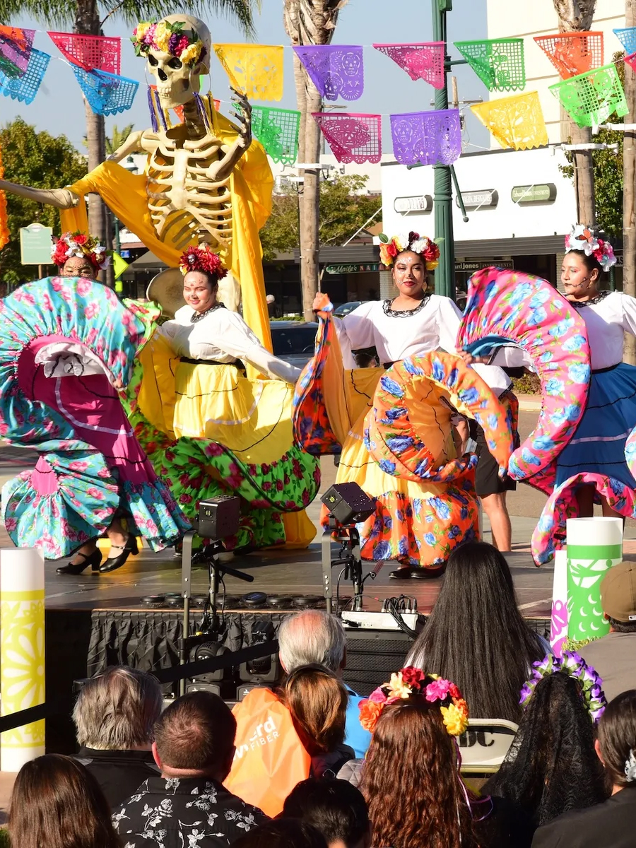 Families gathering at a colorful Día de los Muertos celebration with marigolds, papel picado and glowing ofrendas.