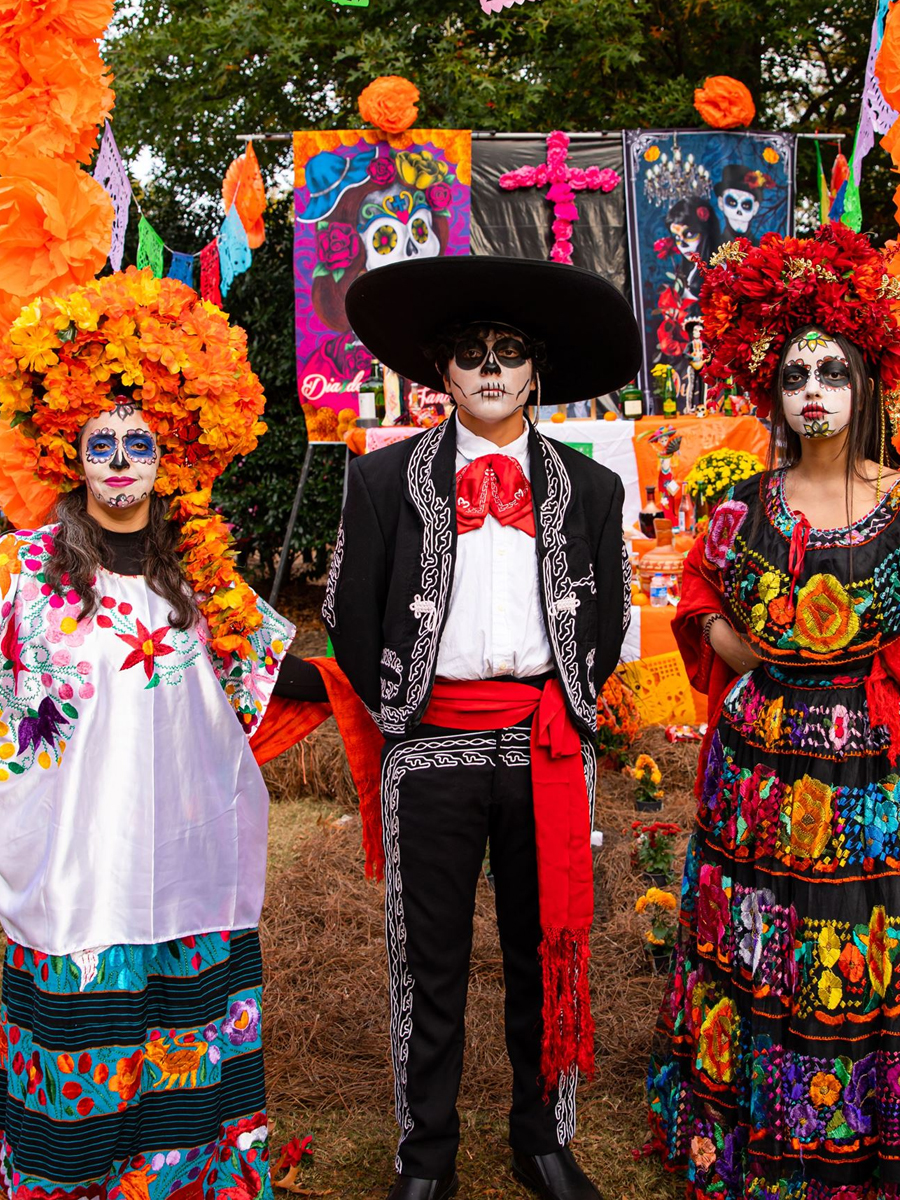 Cultural dancers performing in colorful traditional dress during a Día de los Muertos celebration.
